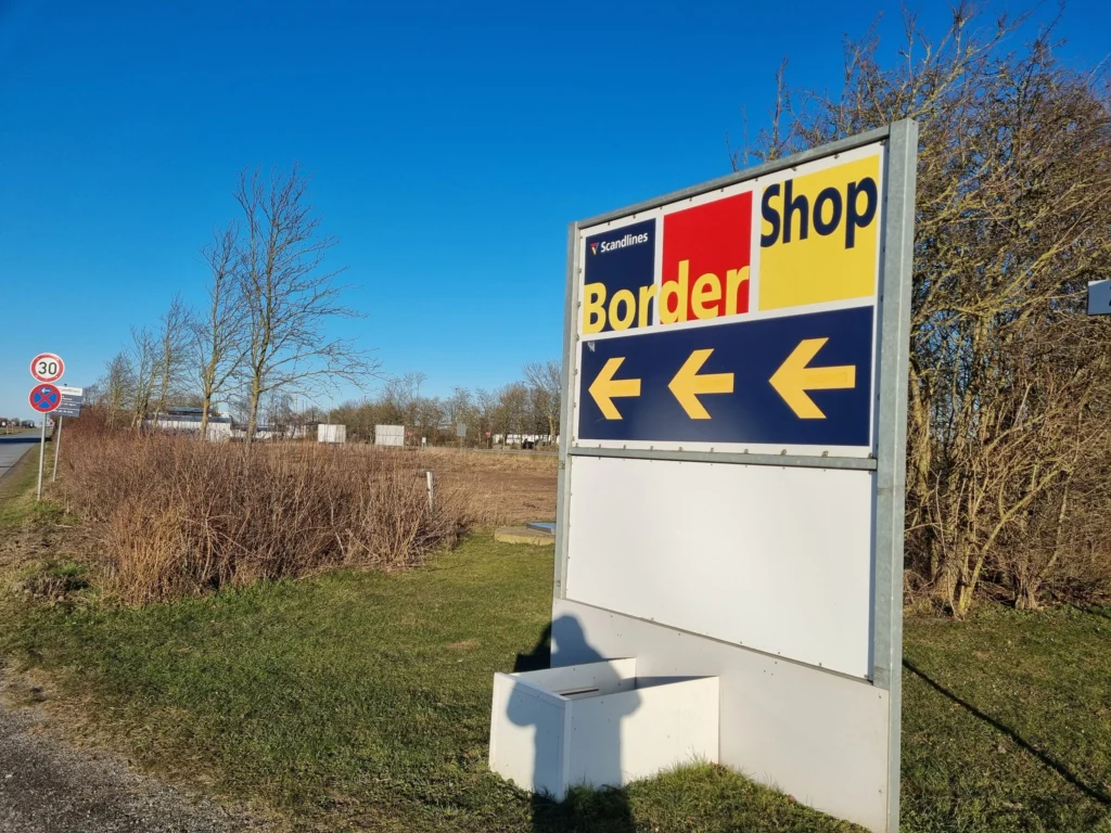 BorderShop-bord met pijlen bij de inrit van de haven van Puttgarden