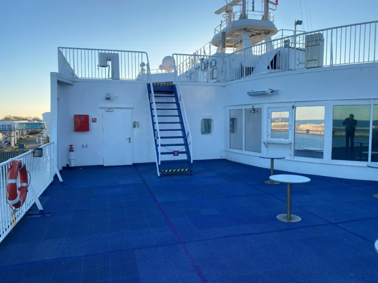 Het zonnedek van de ferry met blauwe vloer en trap naar het bovendek